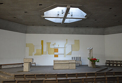 Zu sehen ist der Altarraum in der Kirche St. Josef in Heslach mit dem Mosaik im Hintergrund und dem runden Lichtfenster direkt über dem Altar.