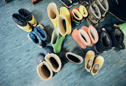 Zu sehen sind viele Gummistiefel in Kindergröße, die auf dem Boden in einer der katholischen Kitas in Stuttgart stehen.